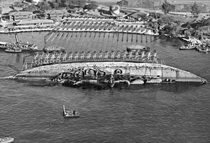 NASPH ^118506- 19 March 1943. USS Oklahoma- Salvage. Aerial view toward shore with ship in 90 degree position. - NARA - 296975