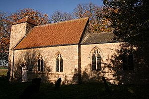 A small stone church seen from the southeast; at the far end is a short tower with a hipped roof