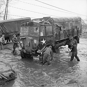 Dutch boys help British troops clean an AEC Matador lorry in a village stream, 25 November 1944. B12100