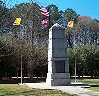 Stone obelisk monument with four flags of the US, Georgia, and Cherokee flying around it