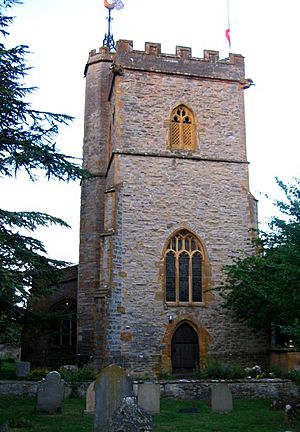 Stone square tower with gravestones in the foreground.