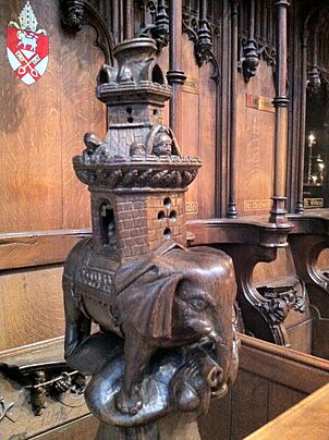 A carved wooden elephant with a very tall castle on its back, and small figures peering out over the battlements