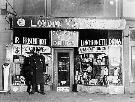 A New York City police officer standing in front of the drugstore where gangster Vincent Coll was murdered.