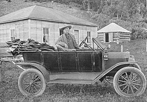 Kootenai Brown leaning against an automobile in front of his cabin (3380765308).jpg