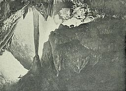 Calcite column and flowstone formations in a grainy black-and-white photo