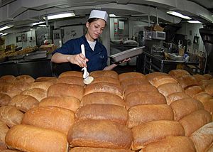 US Navy 090716-N-6720T-017 Culinary Specialist Seaman Samantha Garza butters loaves of fresh baked bread in the bakeshop aboard the aircraft carrier USS George Washington (CVN 73)
