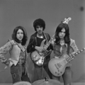 The band pose with their instruments for a black-and-white photo and look to the camera