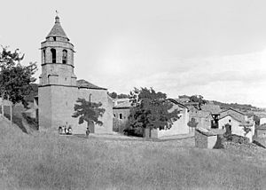 El poble de Castigaleu amb l'església i un grup de persones (cropped)