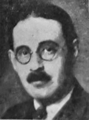 Photograph of a man with circular glasses and a thick black mustache