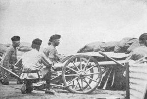 Three artillerymen crouch behind a small 2.5 inch "Screw Gun" employed in the defence of Kimberley