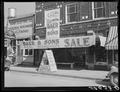 Signs on store window advertising sales during tobacco auction time in Wake County. Zebulon, North Carolina