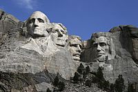 Heads of four presidents carved into the mountain with blue sky