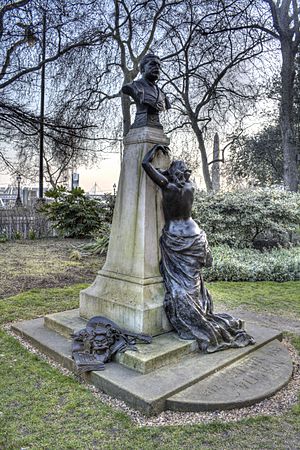 A bronze and stone memorial to Arthur Sullivan. A bronze bust of Sullivan stands on a granite pedestal. A figure of a crying muse leans against the plinth. On the base, bronze sculptures of sheet music, the masks of comedy and tragedy and a mandolin.