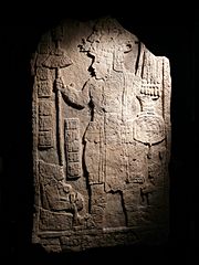 An upright stone slab with the front face flat and inscribed with two elaborately dressed figures facing each other, with a double column of hieroglyphs between them.