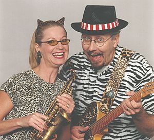 A smiling woman and man holding musical instruments