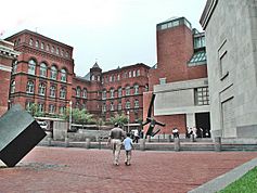 Raoul Wallenberg Place Entrance of USHMM. Three large façades made of brick and limestone. In the foreground a black modern art statue.