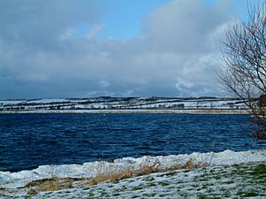 A choppy lake surrounded by snow-covered fields