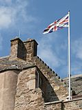 Flag on pole atop a historic building showing the Scottish variant of the Union Flag