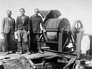 Members of a Sonderkommando 1005 unit pose next to a bone crushing machine in the Janowska concentration camp