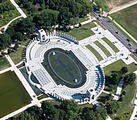 Aerial view of oval-shaped memorial with pond and white walkways