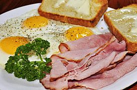Ham and eggs served with thinly-sliced ham and fried eggs prepared "sunny side up", served with toast