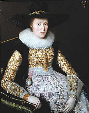 Portrait of a lady wearing a wide hat, embroidered jacket, and an apron