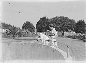 A man and woman standing beside the railing of an animal enclosure at Auckland Zoo (AM 74640-1)