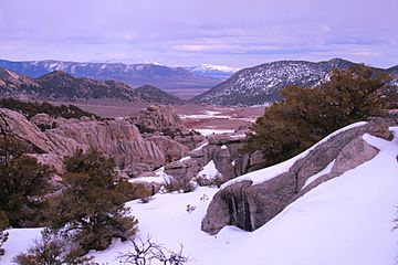A photo taken from the City of Rocks National Reserve with the Black Pine Mountains in the background and covered in snow