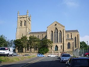 A substantial stone church seen from the south; from the left is a tower with pinnacles, a nave with clerestory, a large south transept, and a short chancel