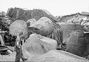 A man wearing military uniform looking towards a pile of damaged metal and concrete objects
