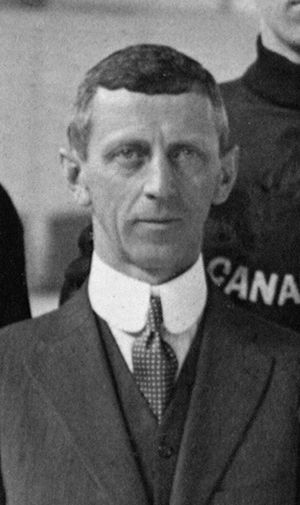 Black and white photo of a middle-aged man wearing a suit and necktie, with a high-collared white dress shirt