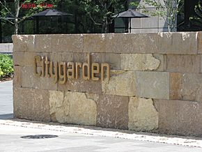 The word "Citygarden" in gold metal letters is fixed to a low wall made of golden-yellow rock bricks.