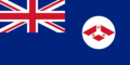 A British Blue Ensign (a blue flag with the Union Jack placed at the top left corner) charged with a white disc containing the badge of the Straits Settlements (red diamond with an inverted white Y; inside that inverted Y is three crowns.
