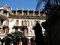 Photograph in a courtyard at the Mission Inn, with four floors of Spanish revival architecture, arches, and tile roofs rising overhead.