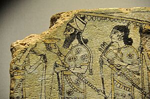 Detail of a glazed terracotta tile from Nimrud, Iraq. The Assyrian king, below a parasol, is surrounded by guards and attendants. 875-850 BCE. The British Museum