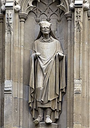 Stone statue of a robed man set in a niche. The top half of the head of the statue is missing.